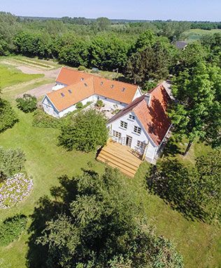 en luftfoto af et stort hus omgivet af træer og græs.