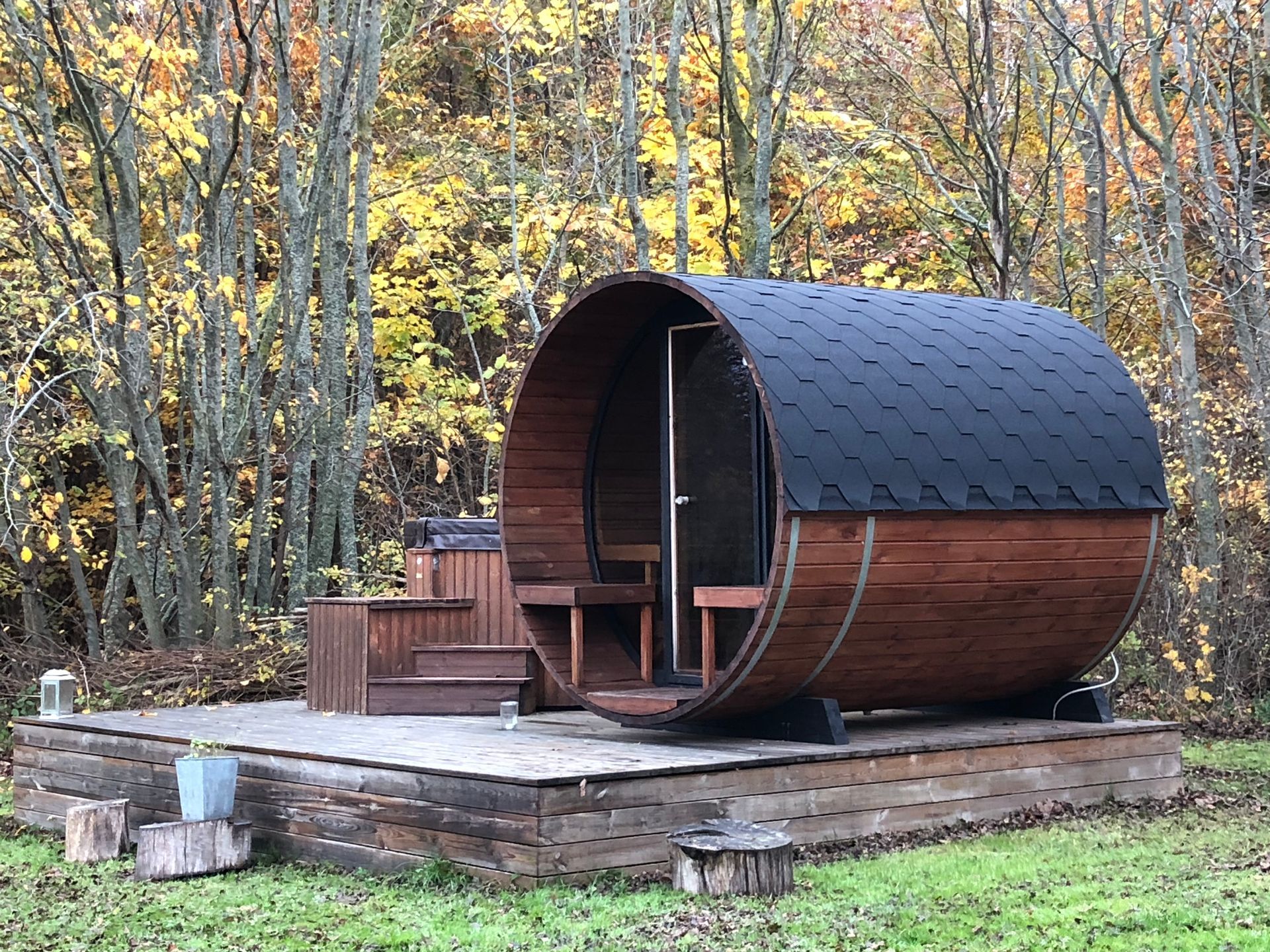 en saunatønde på toppen af en træplatform midt i en skov.