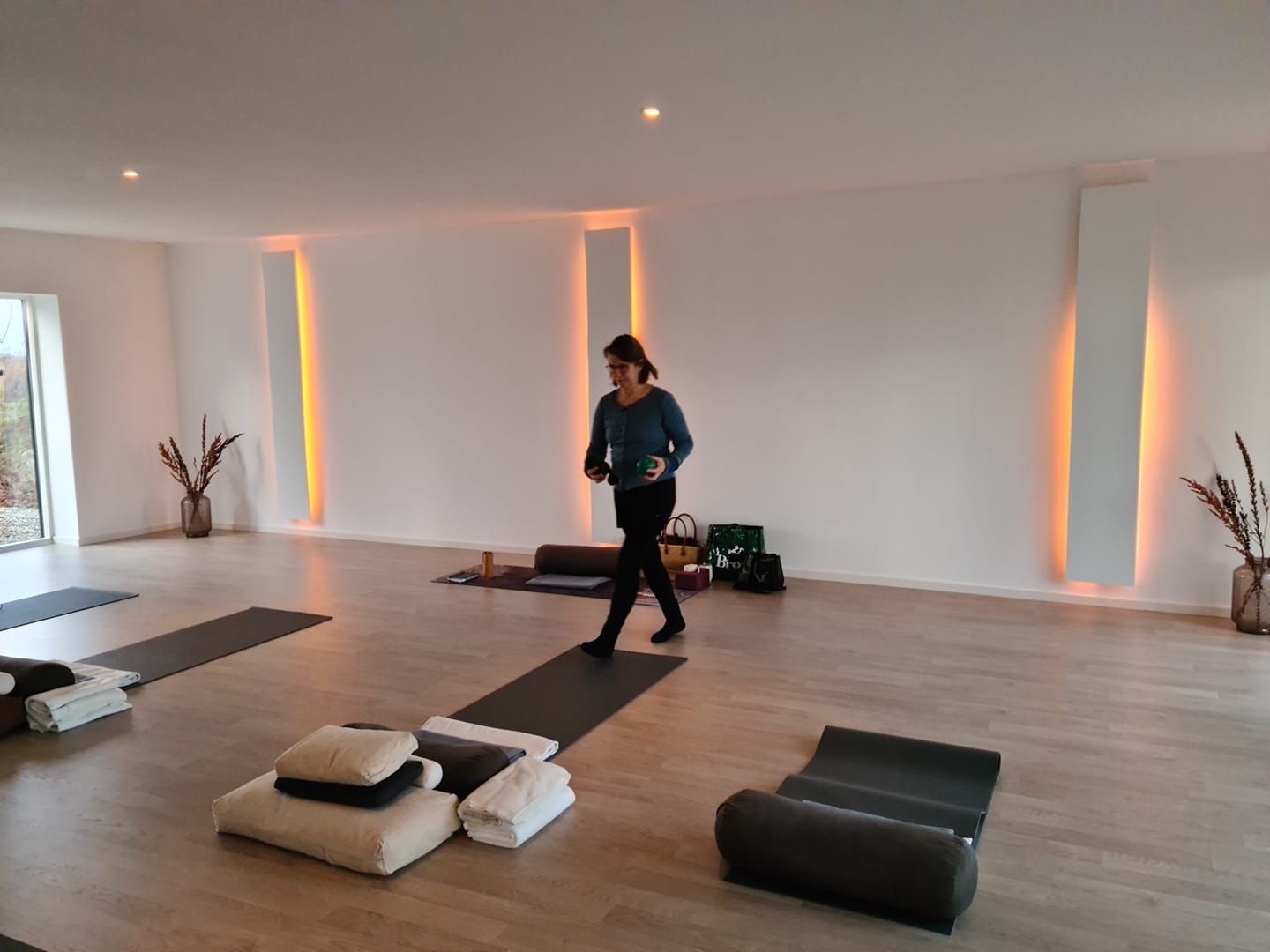 yoga studie med måtter på gulvet og kvinde der går i midten af rummet