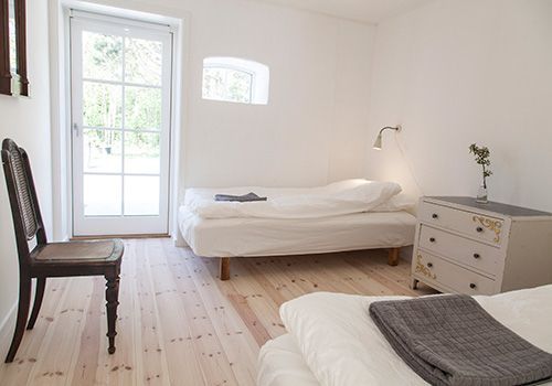 et soveværelse med to senge, en kommode og en stol.