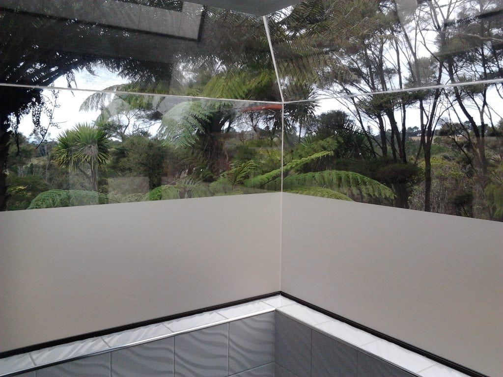 Corner view through a window with frosted bottom. Outside, trees and greenery are visible.