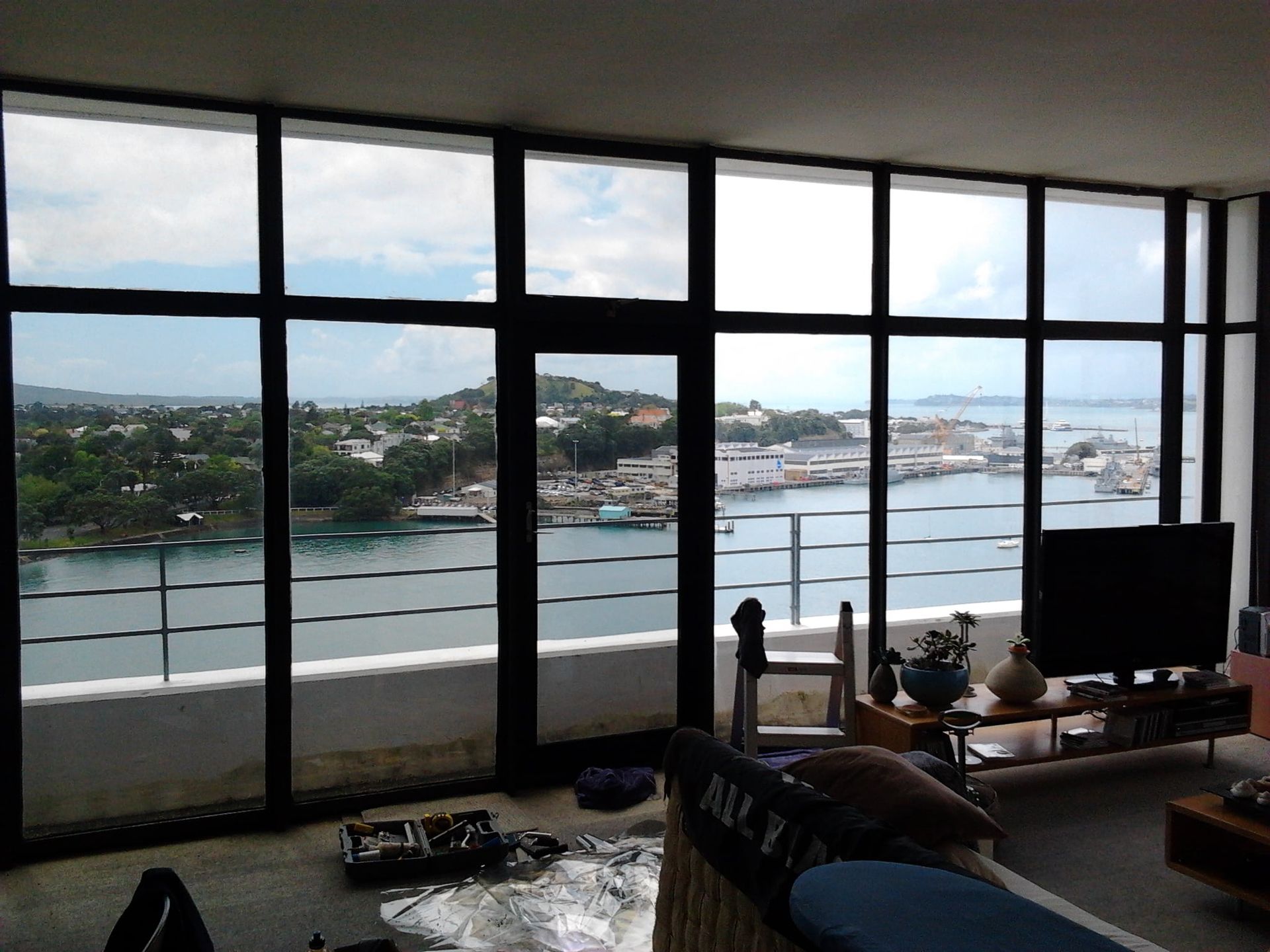 Large windows overlooking harbor. The living room has furniture and TV.