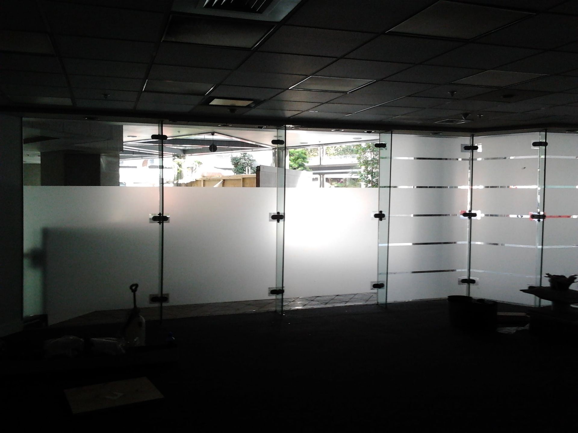 Glass office partition with frosted horizontal stripes and panels, in a dark setting.