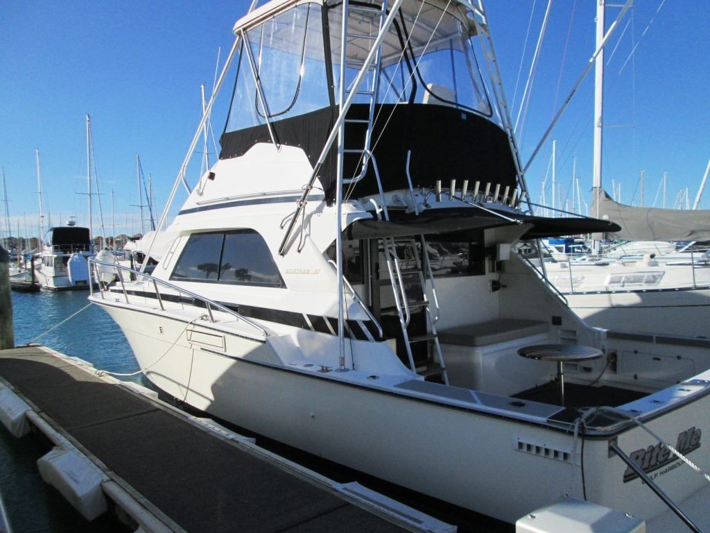White yacht docked at a marina on a sunny day.