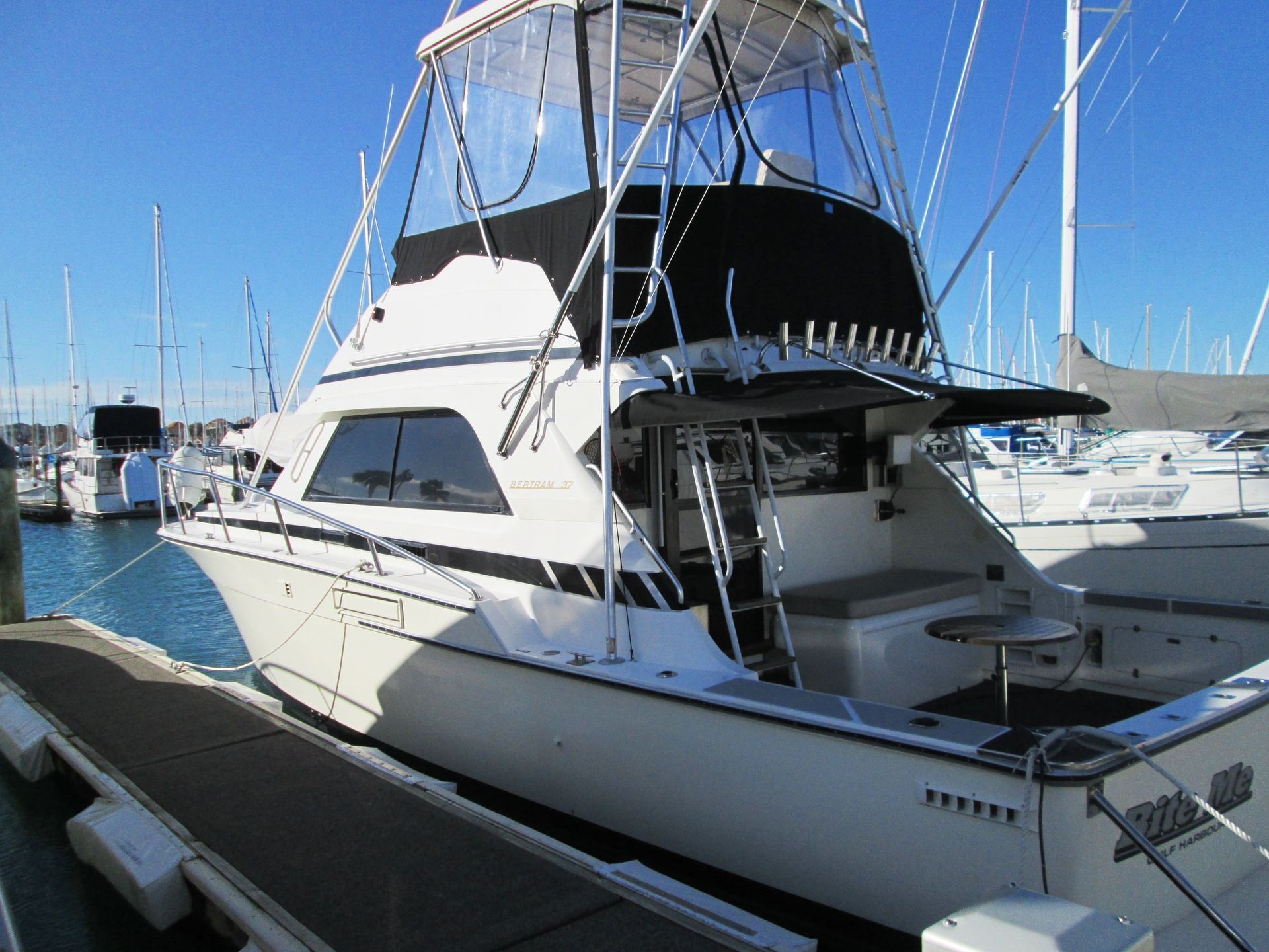 White motorboat docked at a marina on a sunny day.