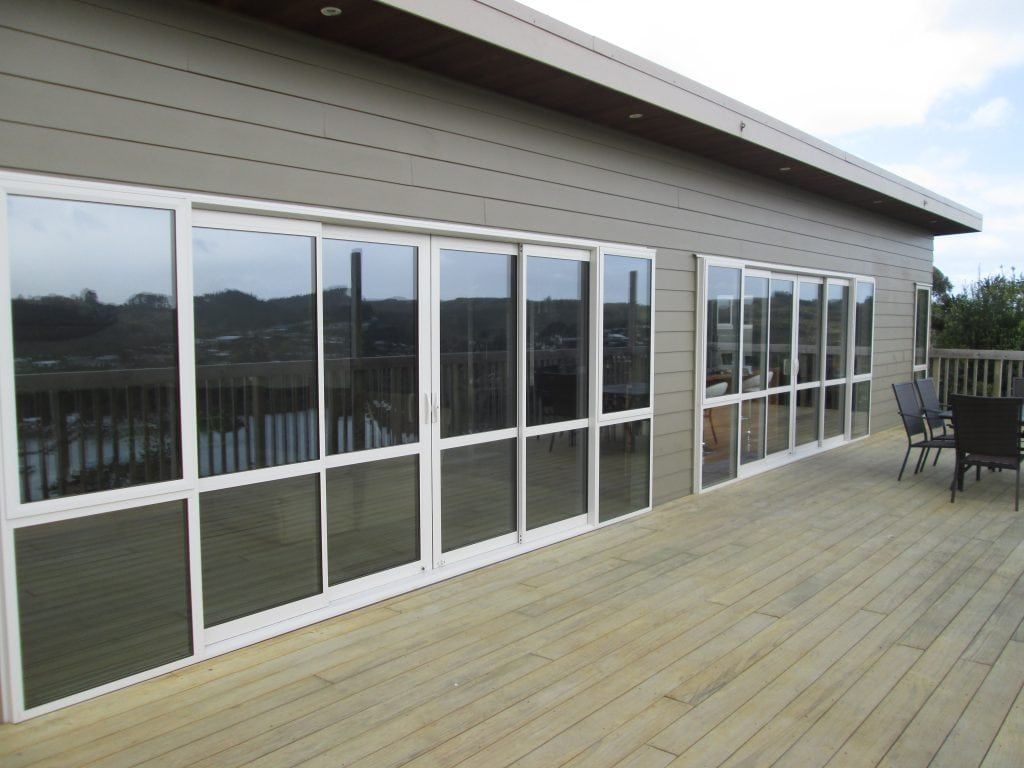 Exterior view of a building with large, reflective windows, deck, and outdoor furniture.
