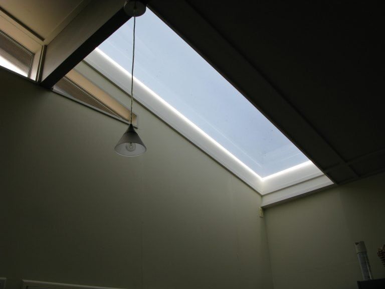 Skylight in a room with a hanging light fixture and neutral-colored walls.