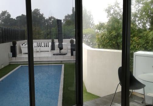 Pool area with a pool, patio furniture, and a foggy view through a glass door.