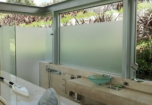 Frosted glass shower with a stone countertop, a sink, and an outdoor view.