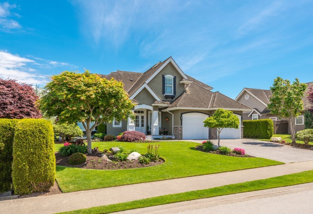 A large house with a lush green lawn and trees in front of it.