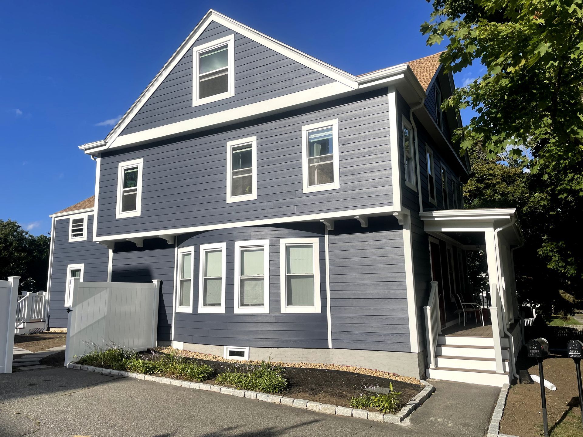The side of a house with a gray siding and two windows.