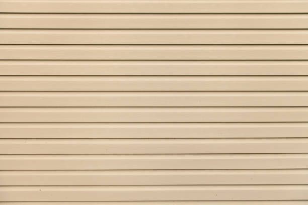 A close-up of a beige vinyl siding wall.