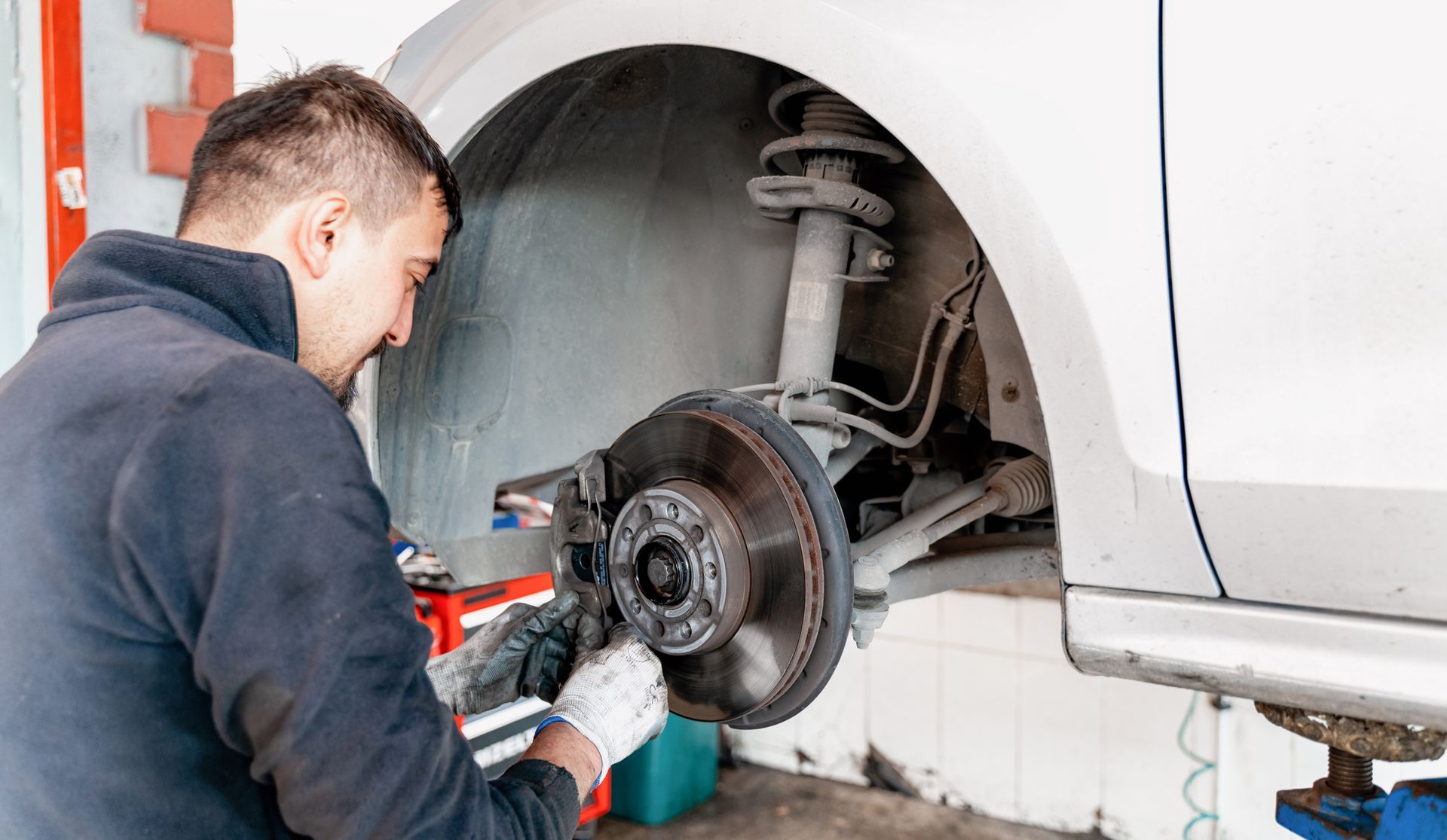 Car mechanic hands replace brakes in garage