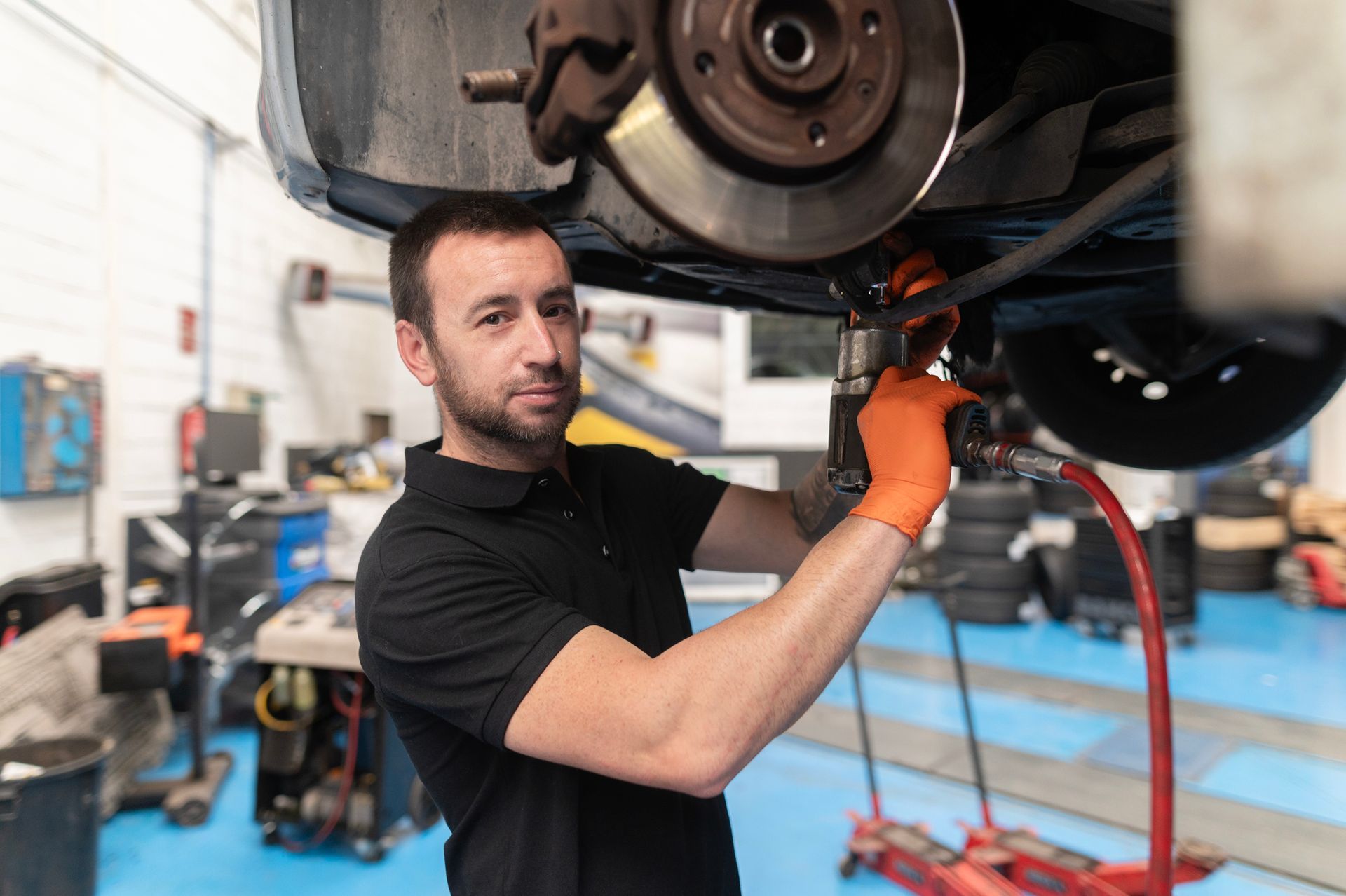 Mechanic repairing car using impact wrench in auto repair shop Mechanic repairing car using impact wrench in auto repair shop