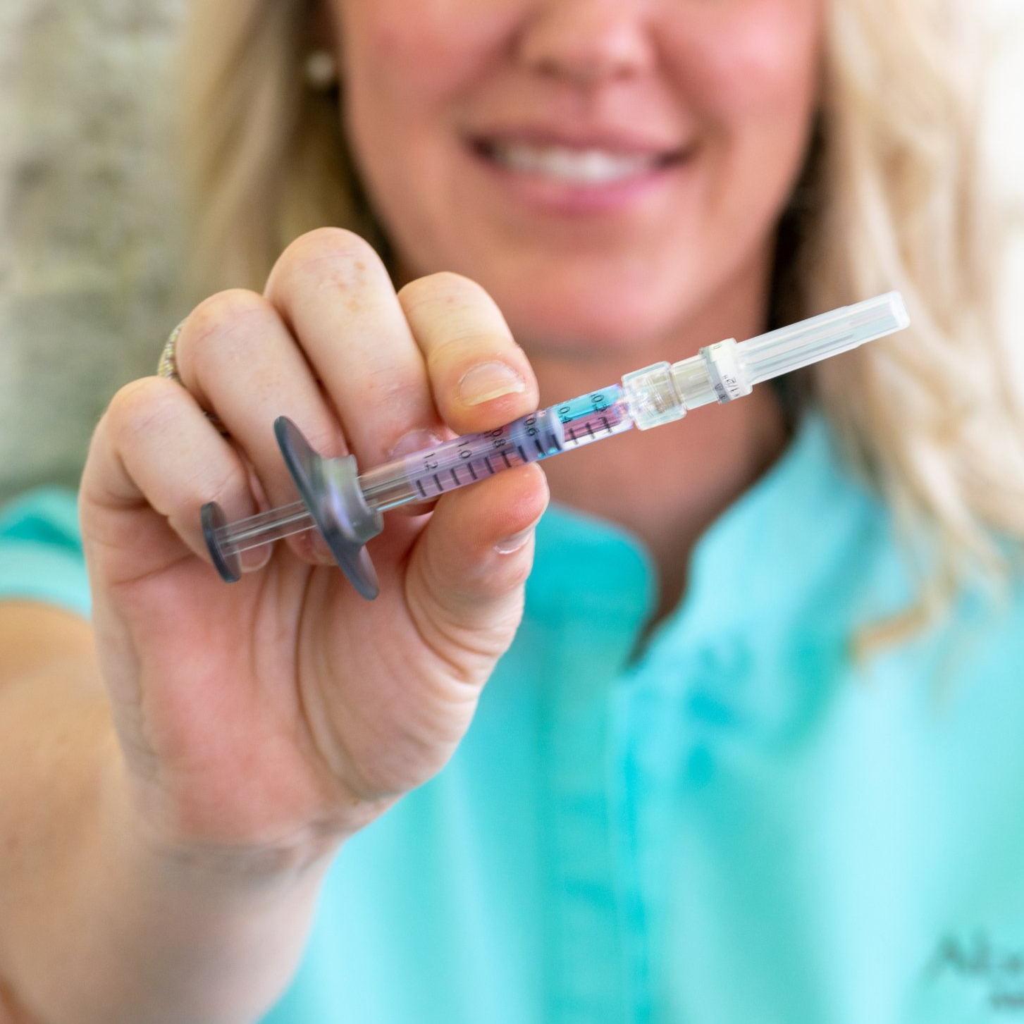 A woman in a blue shirt is holding a syringe in her hand