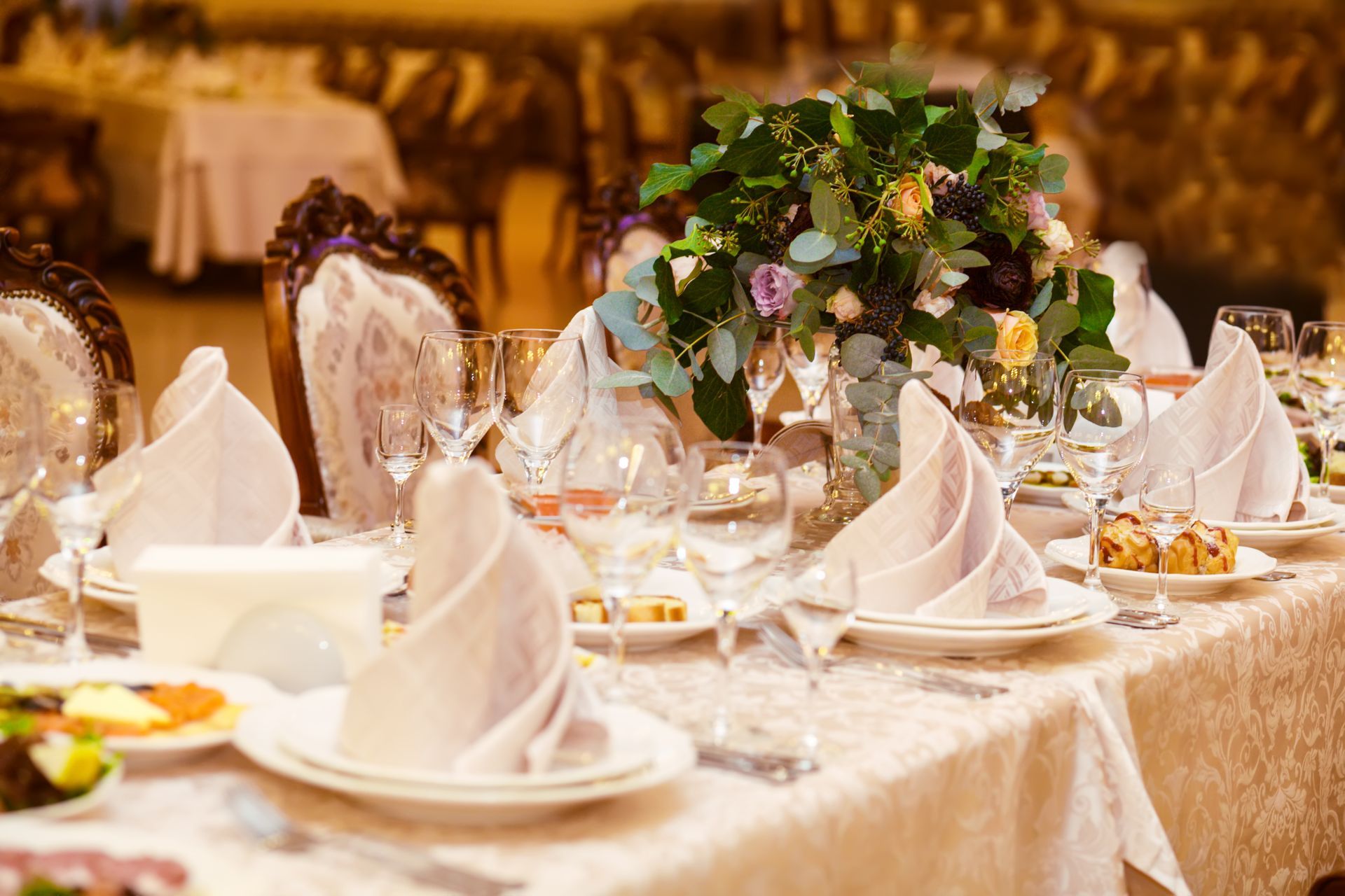 A table set for a wedding reception with plates , glasses , napkins and flowers.