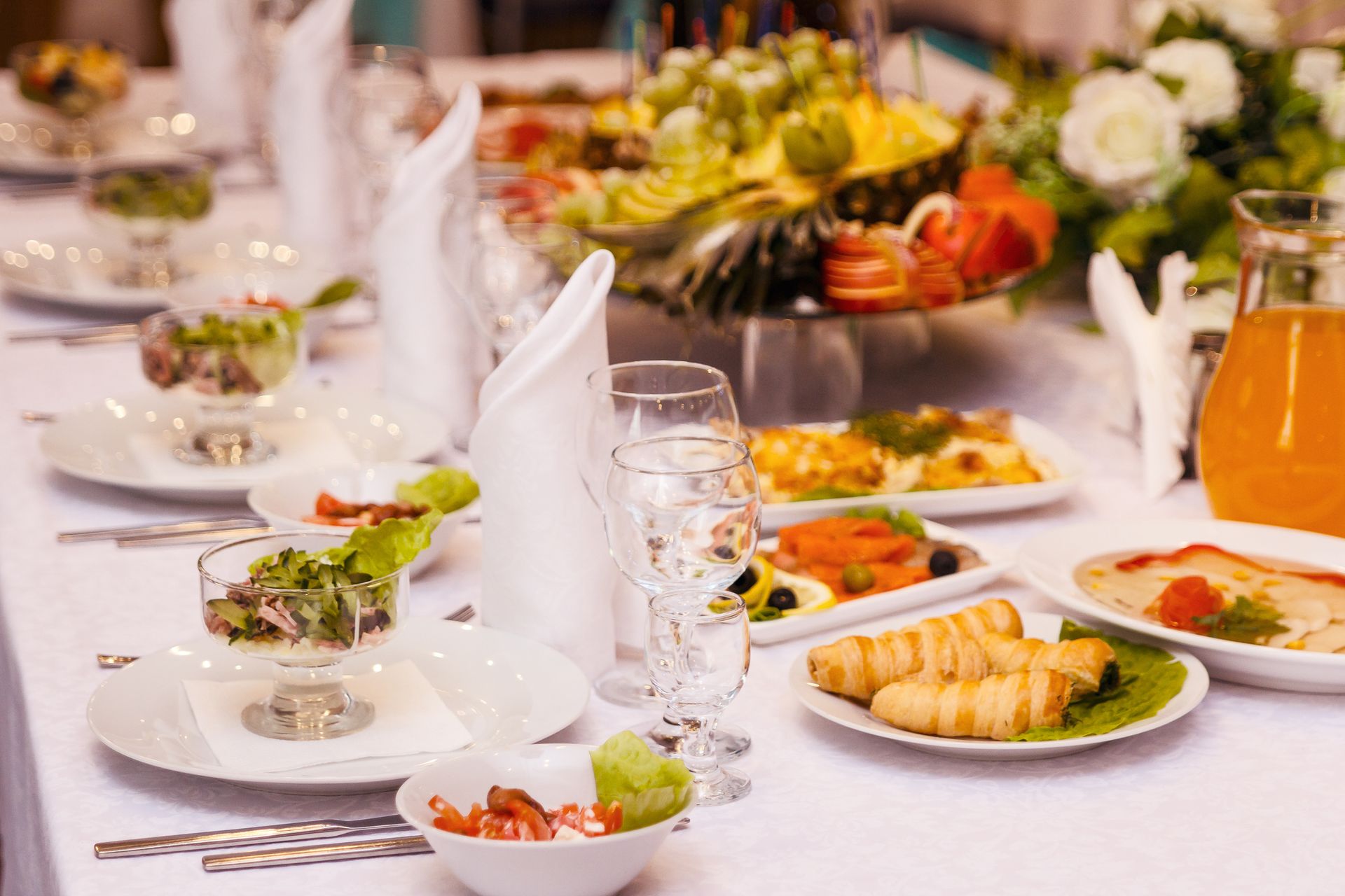 A long table with plates of food and glasses on it.