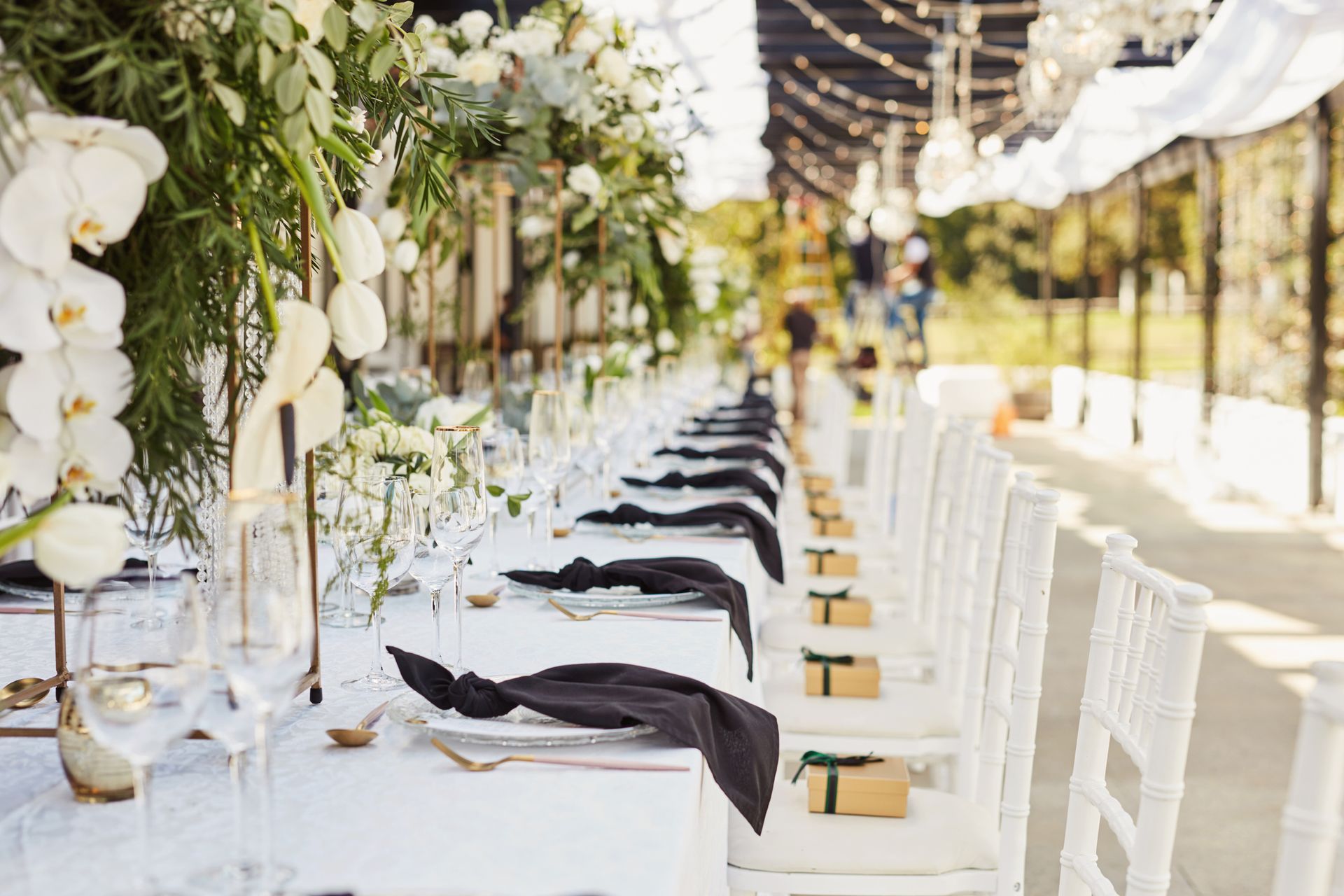 A long table set for a wedding reception with white tables and white chairs.