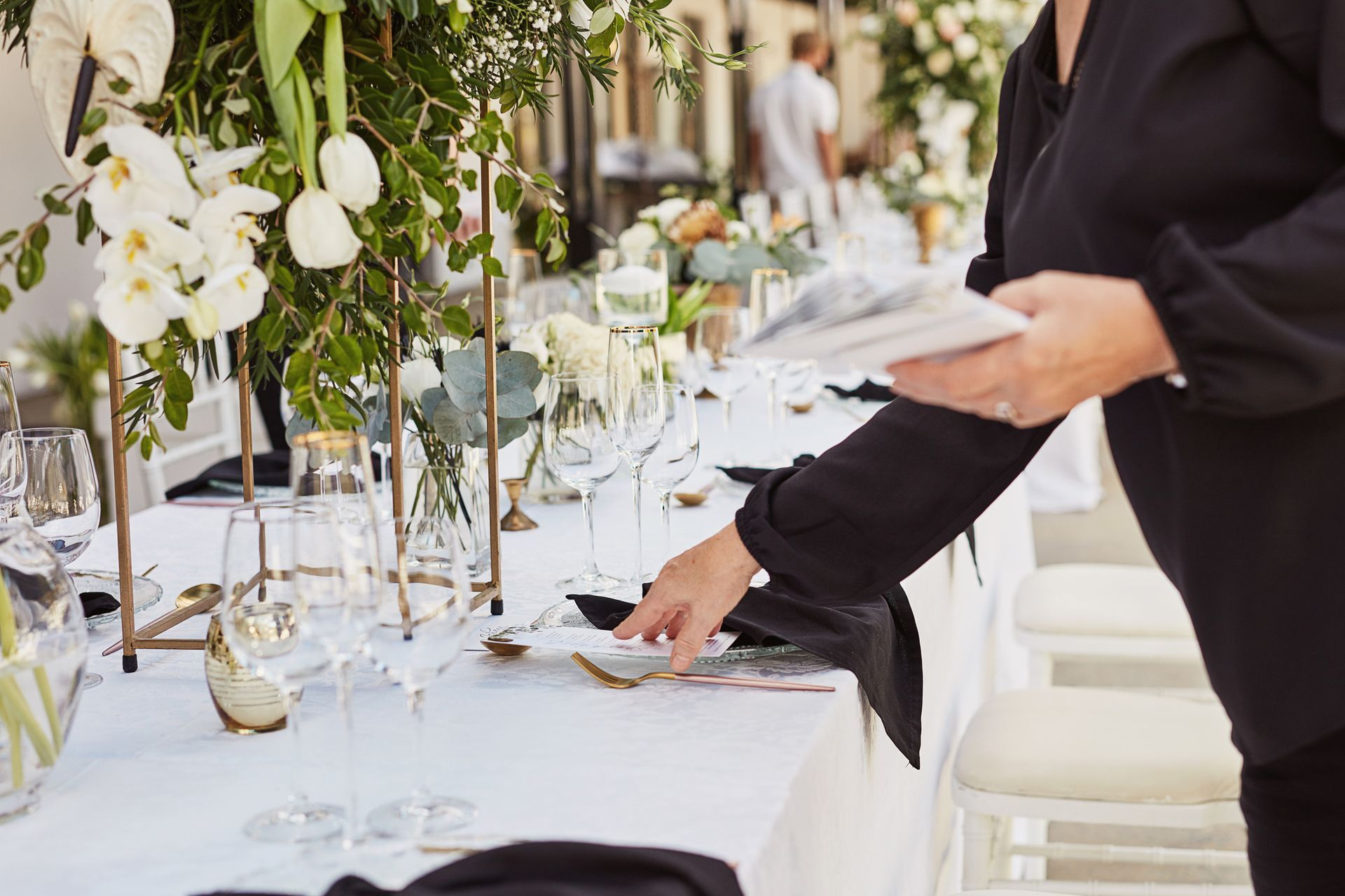 A table set for a wedding reception with plates , wine glasses , and flowers.