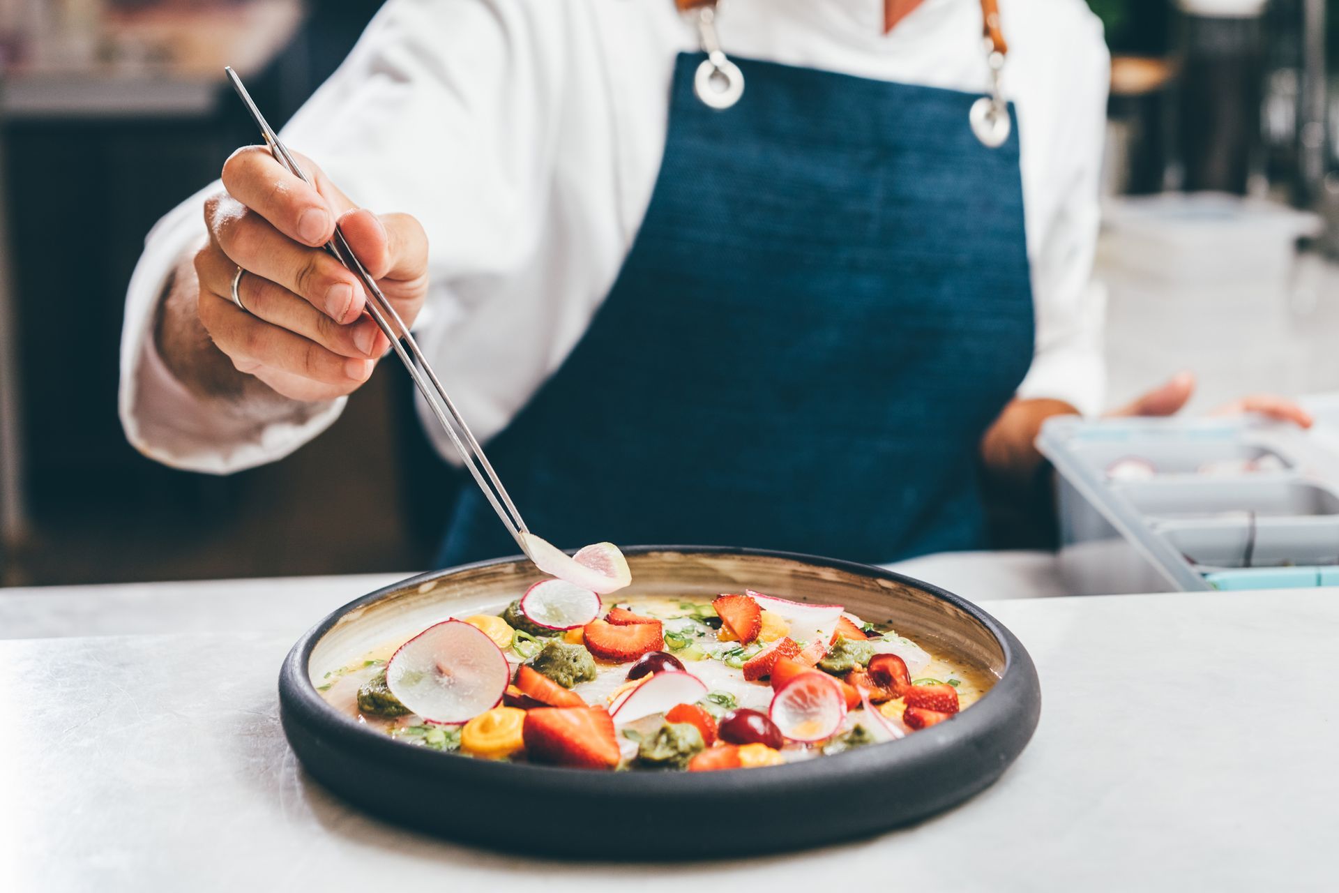 A chef is decorating a plate of food with a spoon.