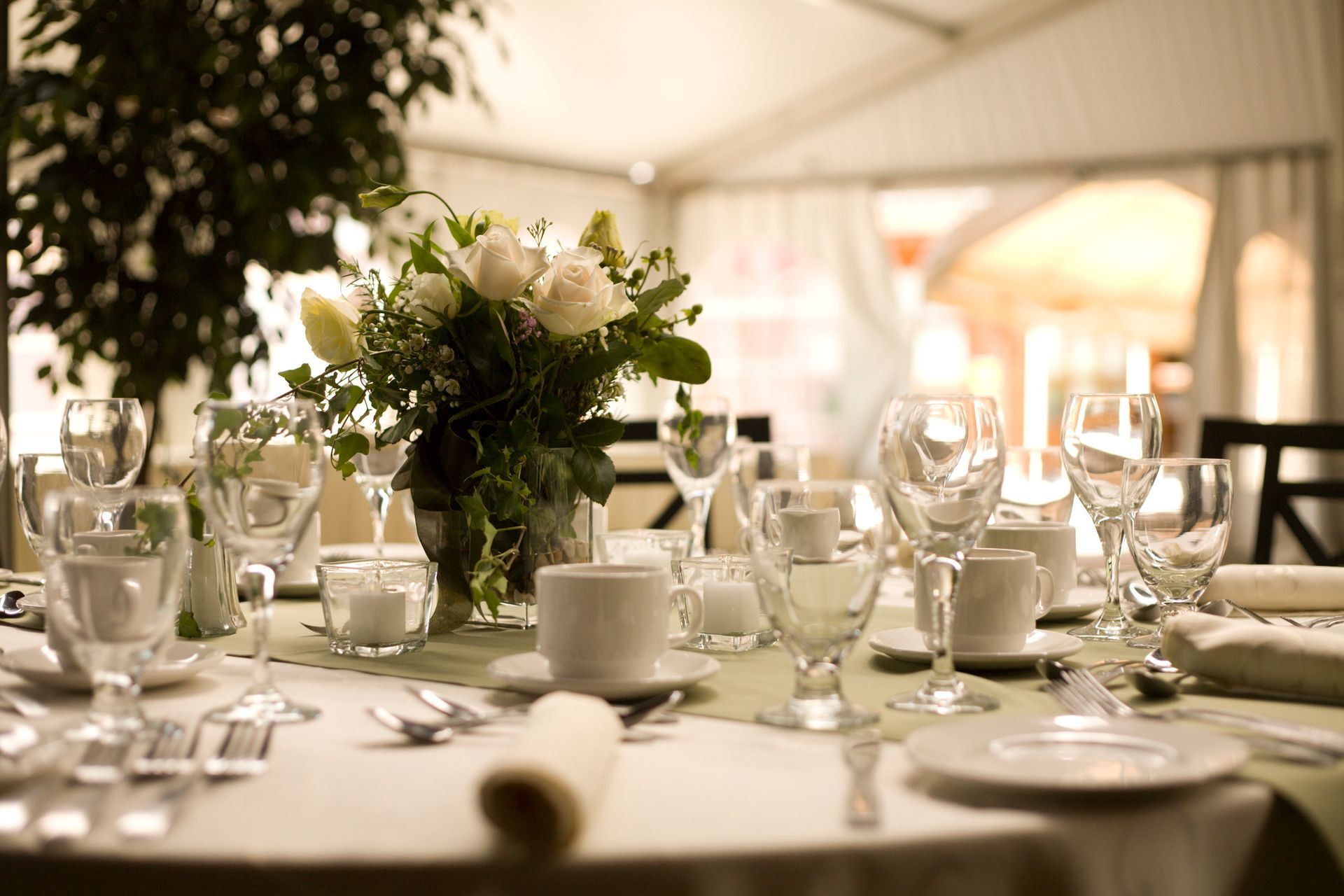 A table set for a wedding reception with a vase of flowers on it