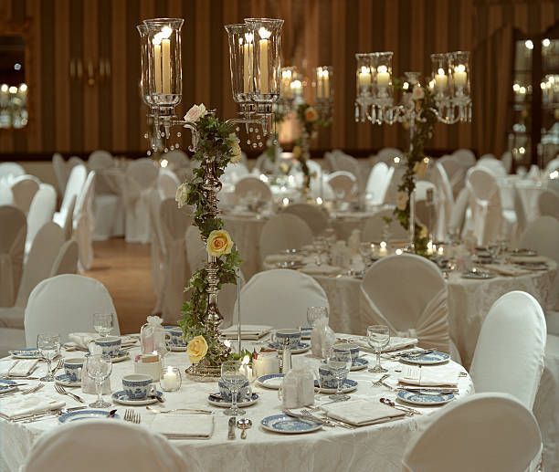 A large room at night with tables and chairs set up for a wedding reception
