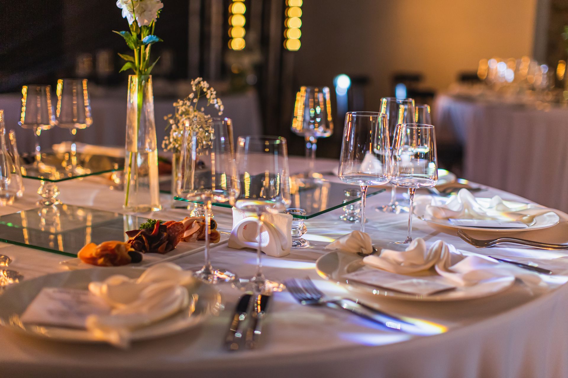 A table set for a wedding reception with plates , glasses , and silverware.