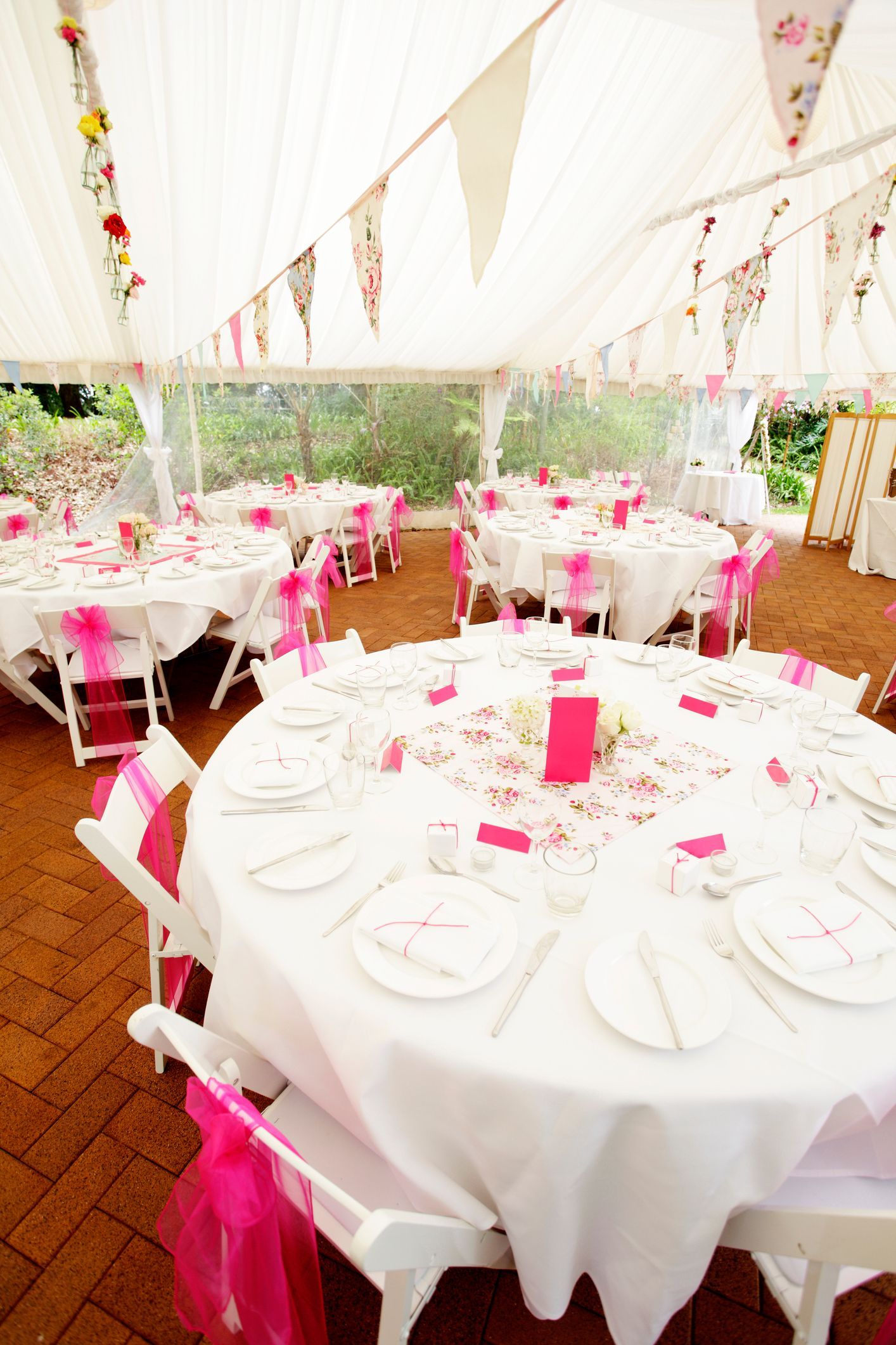 A tent with tables and chairs set up for a wedding reception.