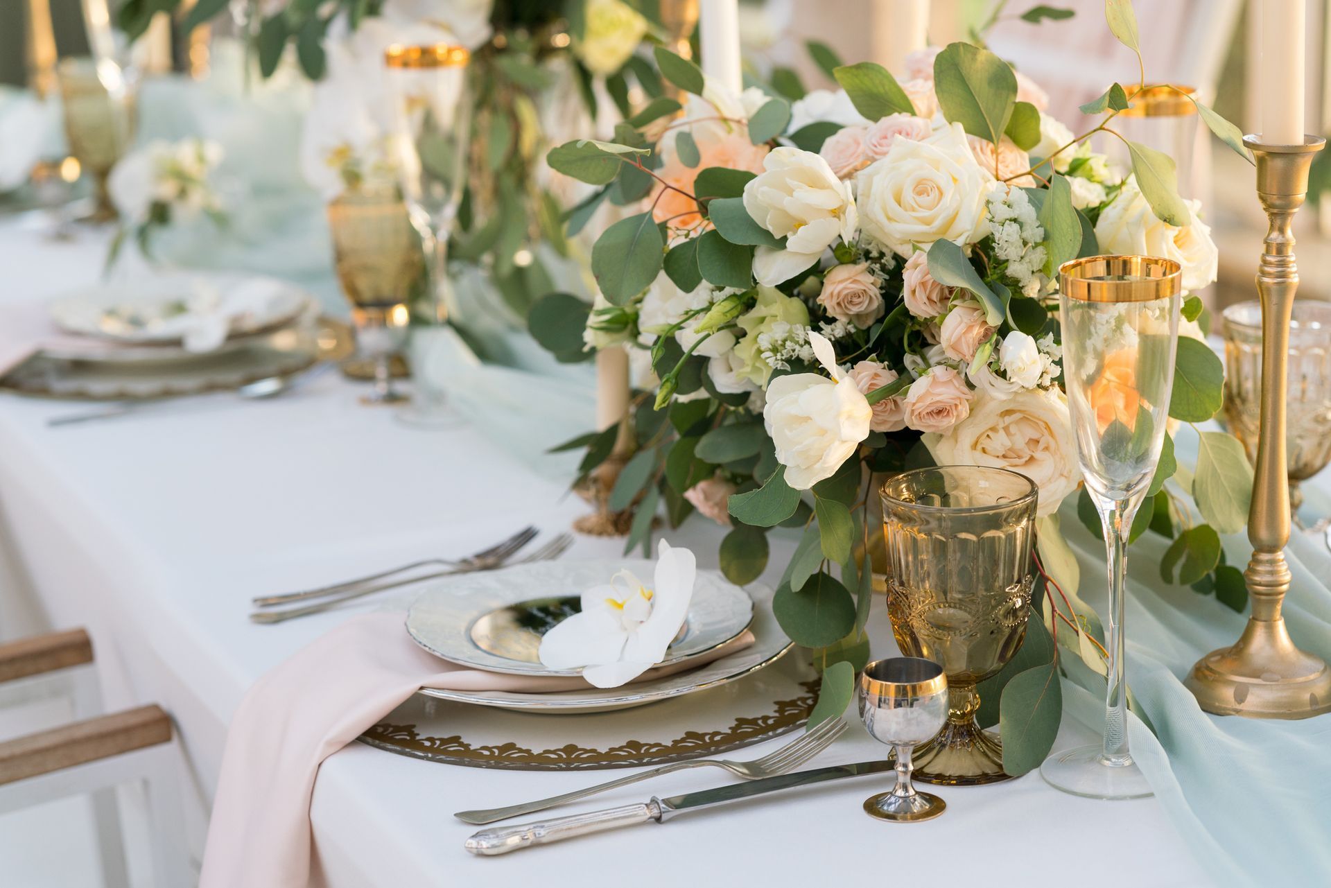 A table set for a wedding reception with plates , silverware , candles and flowers.