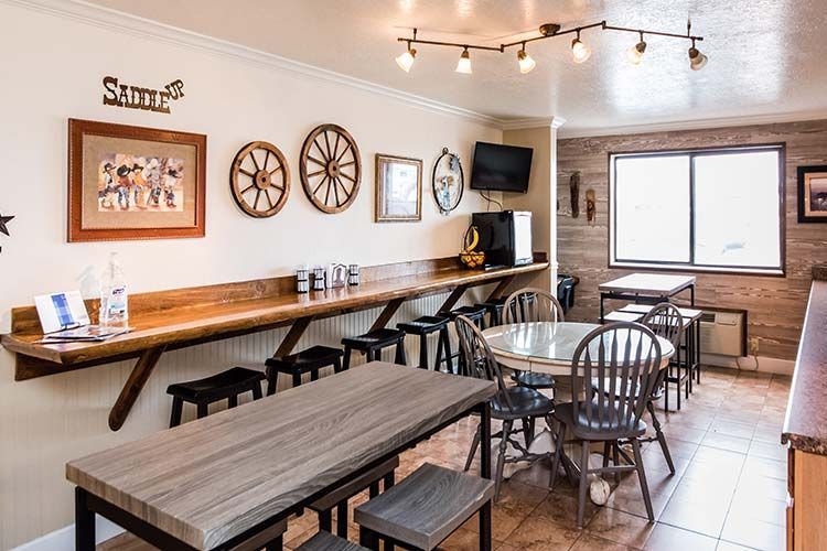 Western-themed dining area with wooden tables, stools, wagon wheel decor, and a coffee machine.