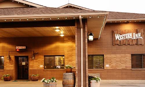 Western Inn exterior with wooden siding, lighted sign, and awning.