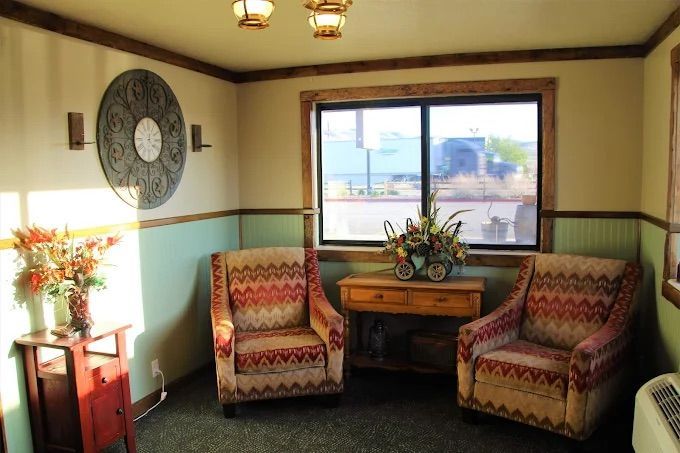 Two patterned armchairs sit near a window in a room with light blue and beige walls.