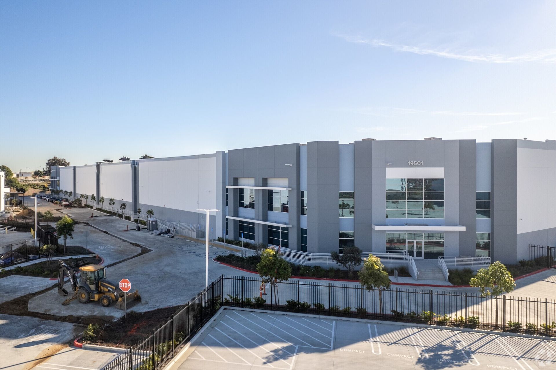 A modern building with a red and gray facade and a glass wall under a blue sky.