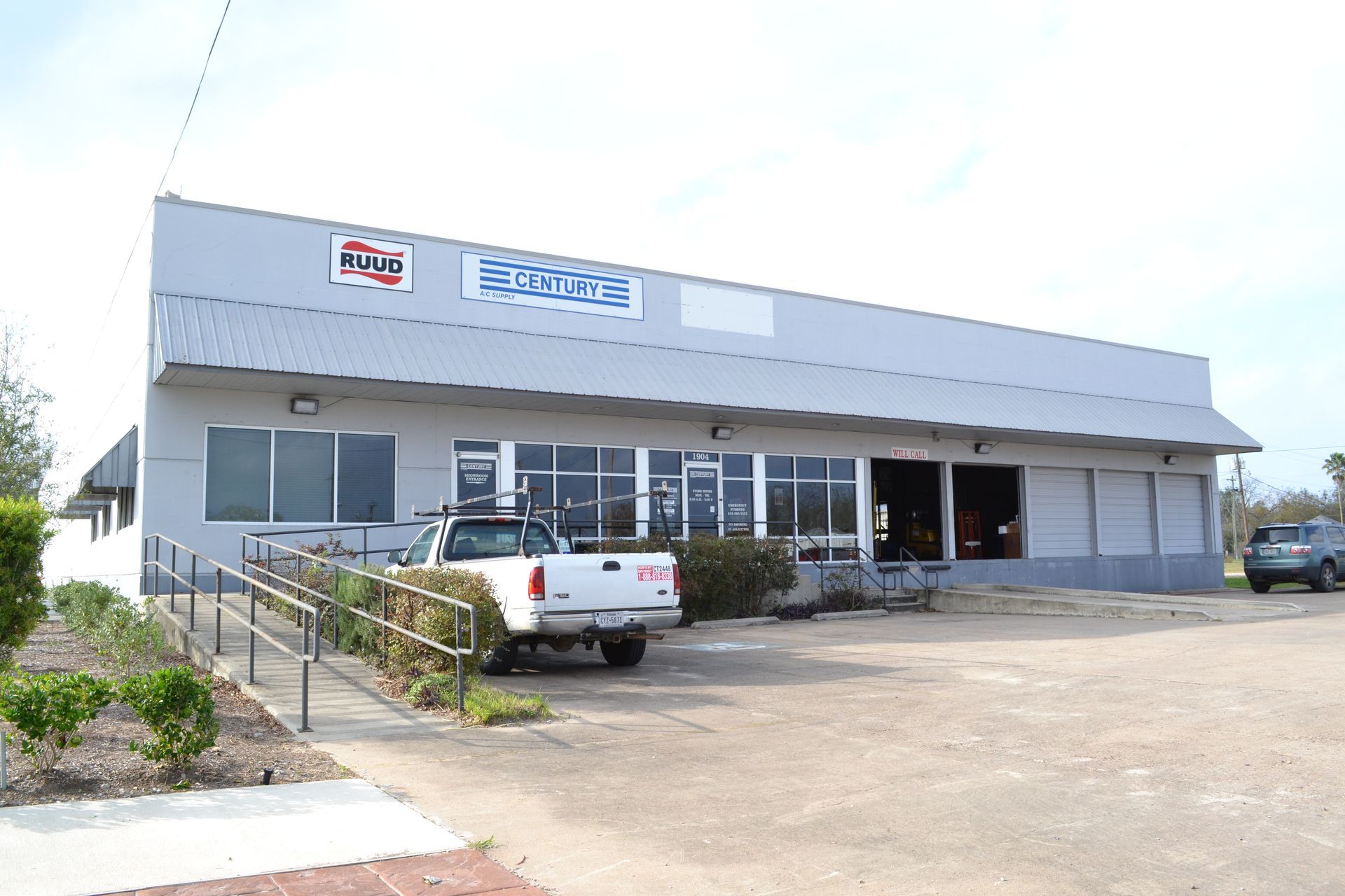 Modern office building with blue-tinted windows, a grassy lawn, and mountains in the background.