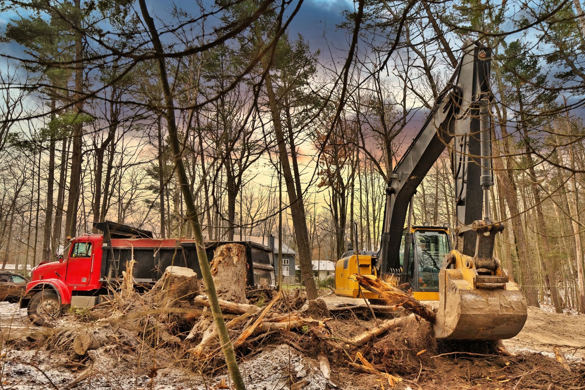 A bulldozer is moving dirt in the woods next to a red truck.