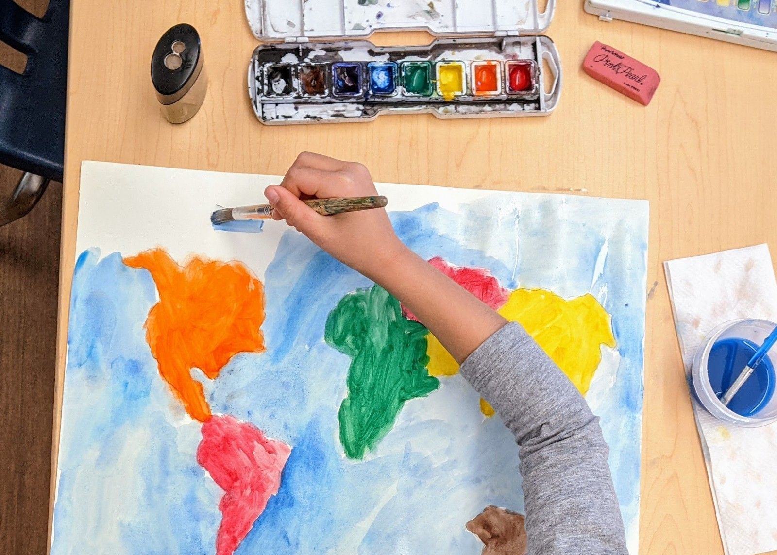 Montessori child painting a world map