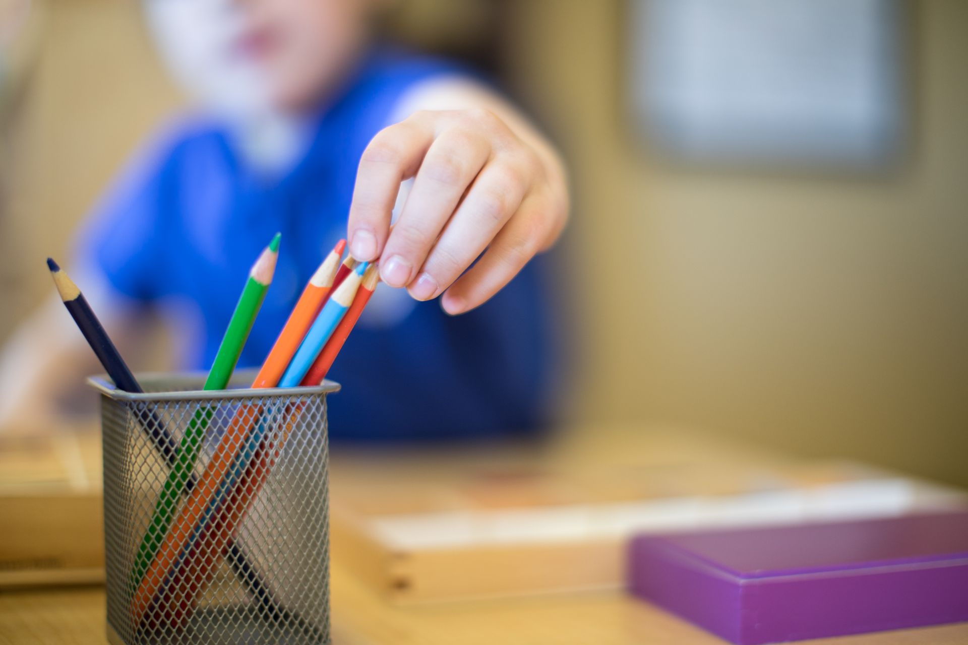 Montessori child grabbing a color pencil