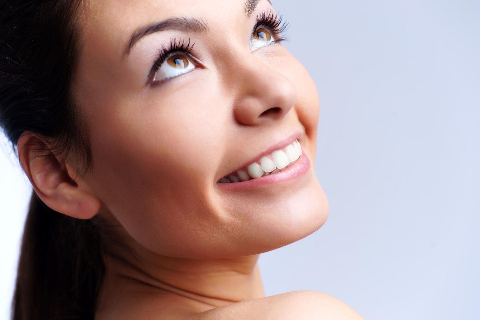 A close up of a woman 's face smiling and looking up.