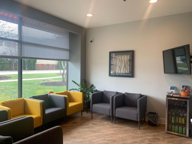 A waiting room with a lot of chairs and a television.