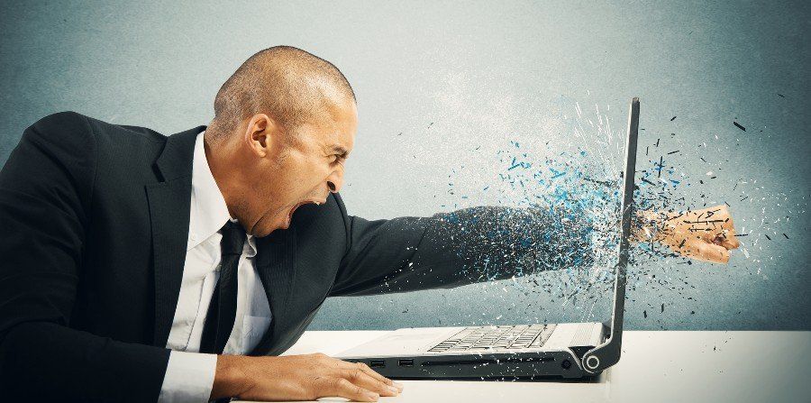 Stressed man punching his computer