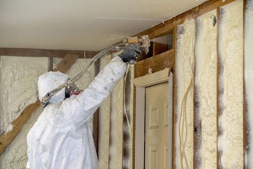 Image of a spray foam contractor spraying a wall. 