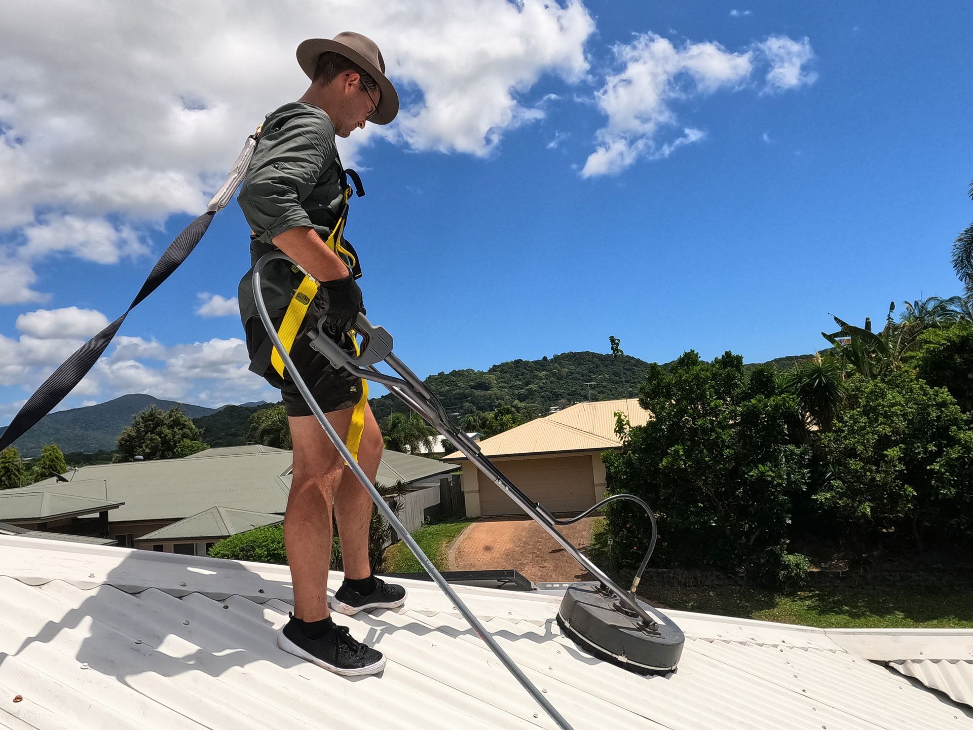 A Man on a Safety Harness Pressure Washing a Roof — Zac's Bin and Pressure Cleaning In Parramatta Park, QLD