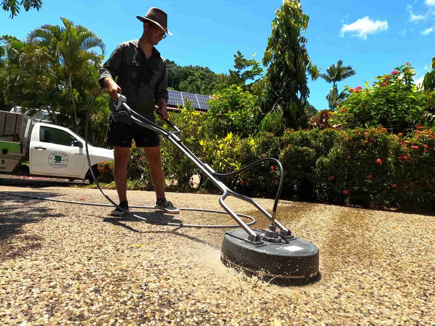 A Man Is Using a Machine to Clean a Driveway — Zac's Bin Cleaning & Pressure Washing Services In Parramatta Park, QLD