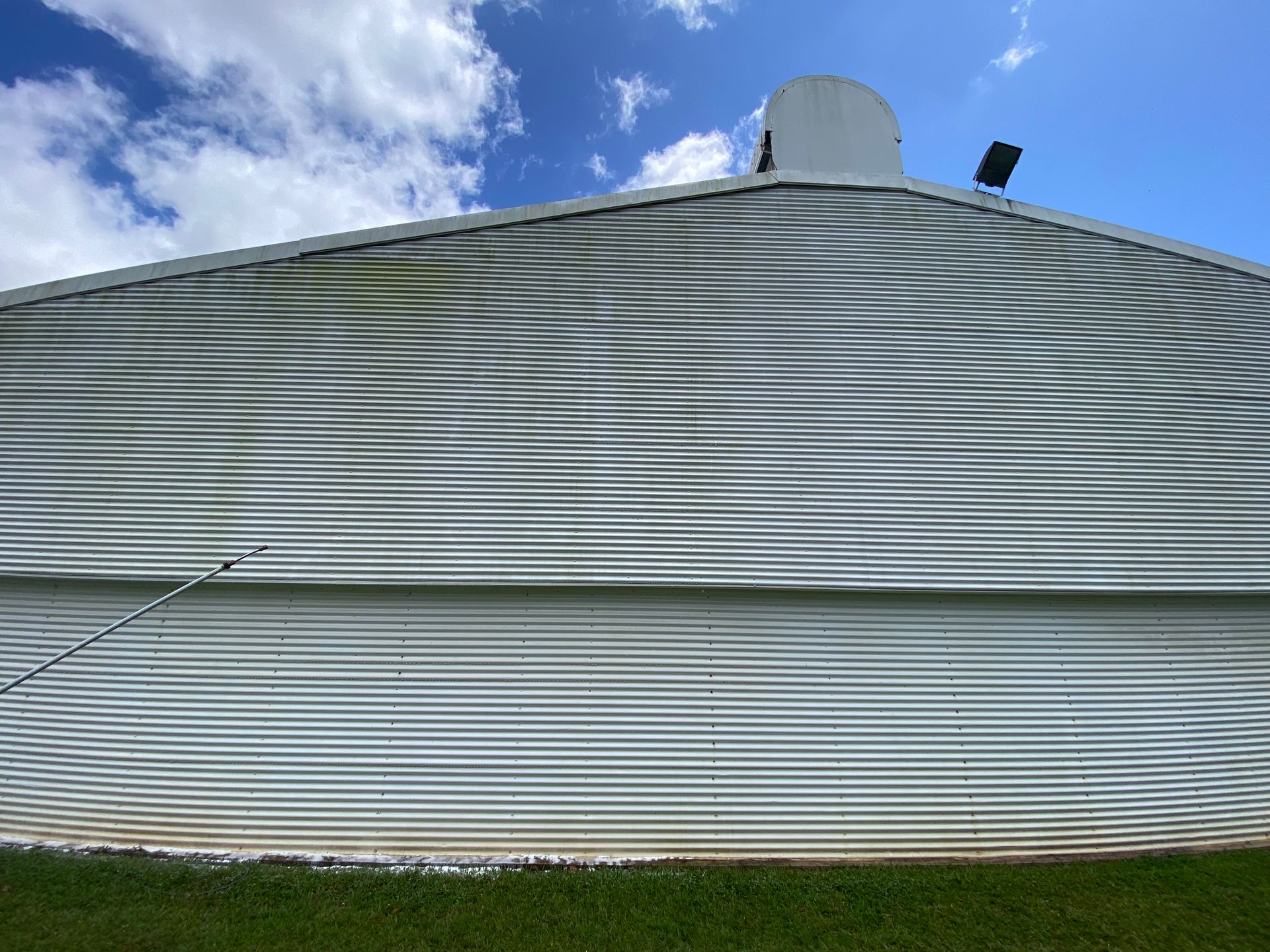 Person Power Washing a Window on a Light-colored House — Zac's Bin and Pressure Cleaning In Parramatta Park, QLD