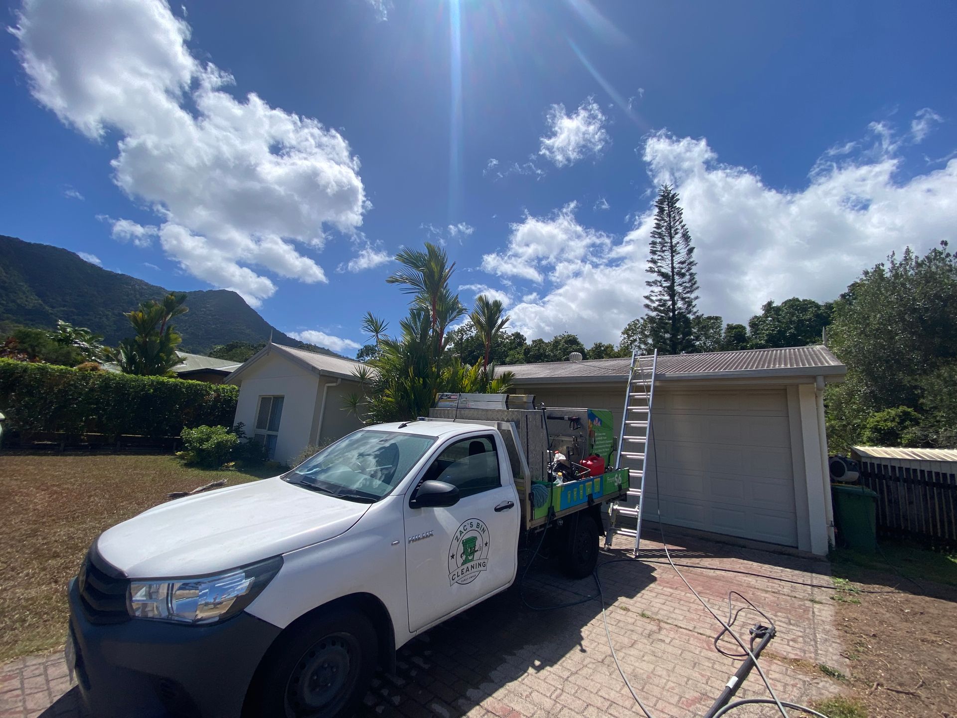 A Man Pressure Washes the Exterior of a White Garage Door and Trim — Zac's Bin and Pressure Cleaning In Parramatta Park, QLD