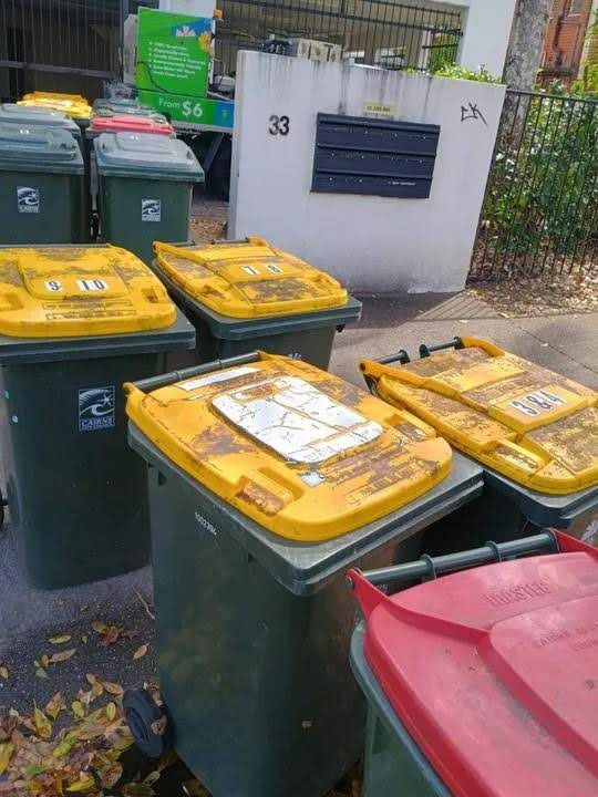 A Group of Recycling Bins Sit Outside a Building — Zac's Bin and Pressure Cleaning In Parramatta Park, QLD