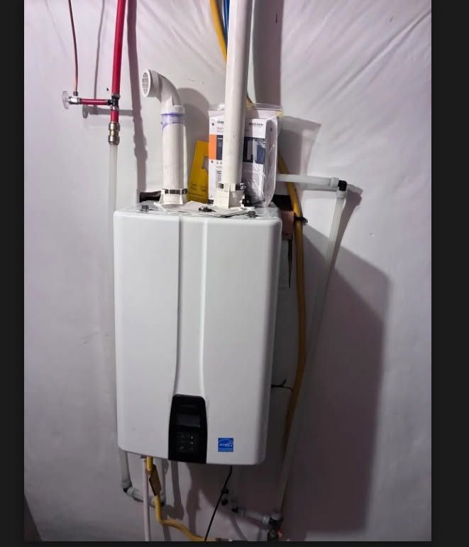 Wall-mounted white water heater with connected pipes and hoses in a utility room