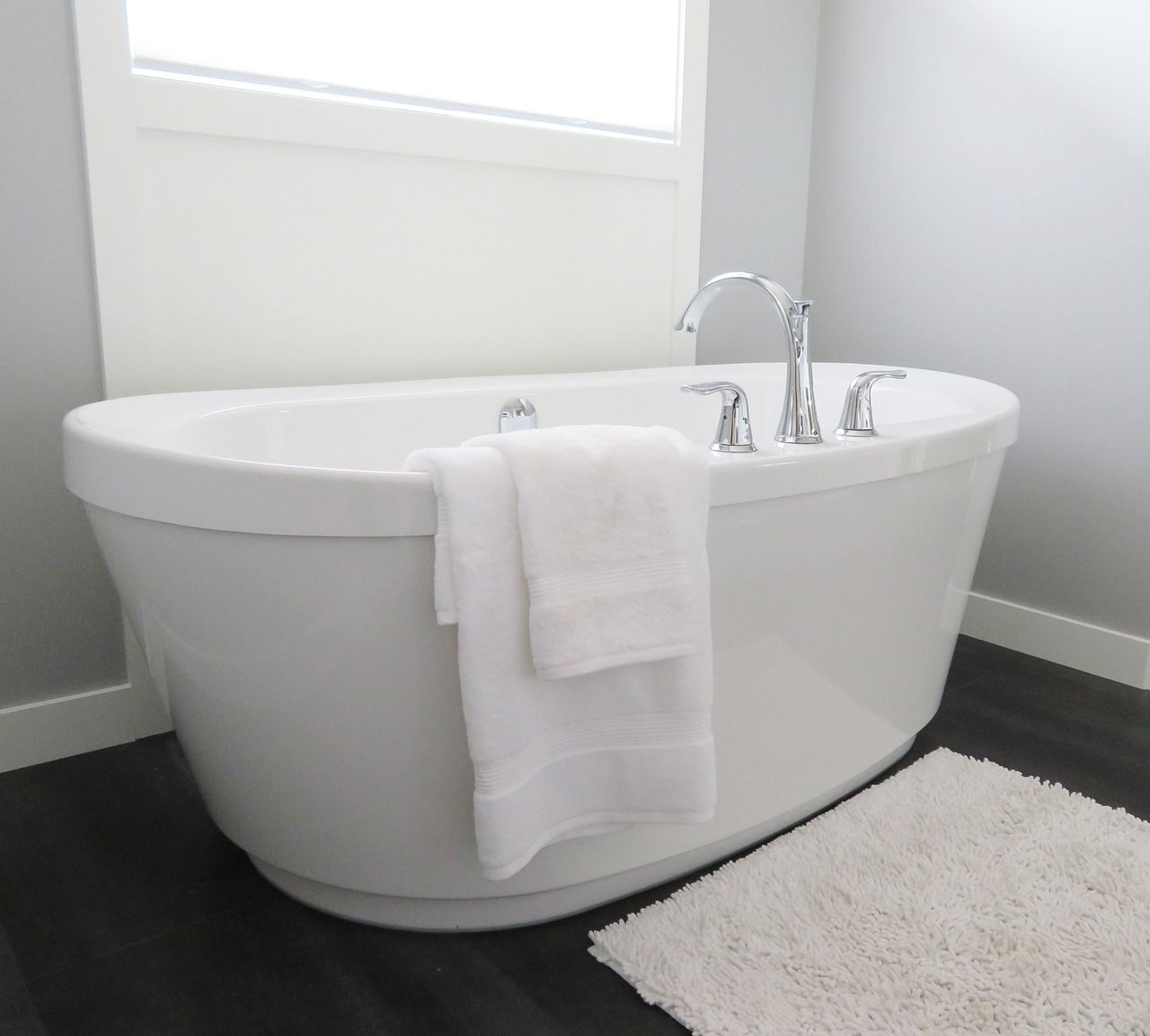 Modern white freestanding bathtub with towel in a bright bathroom
