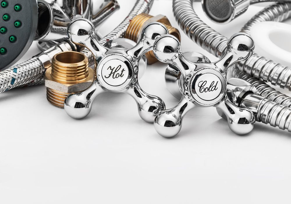 Chrome plumbing fittings and coiled hoses with decorative knobs on a white background