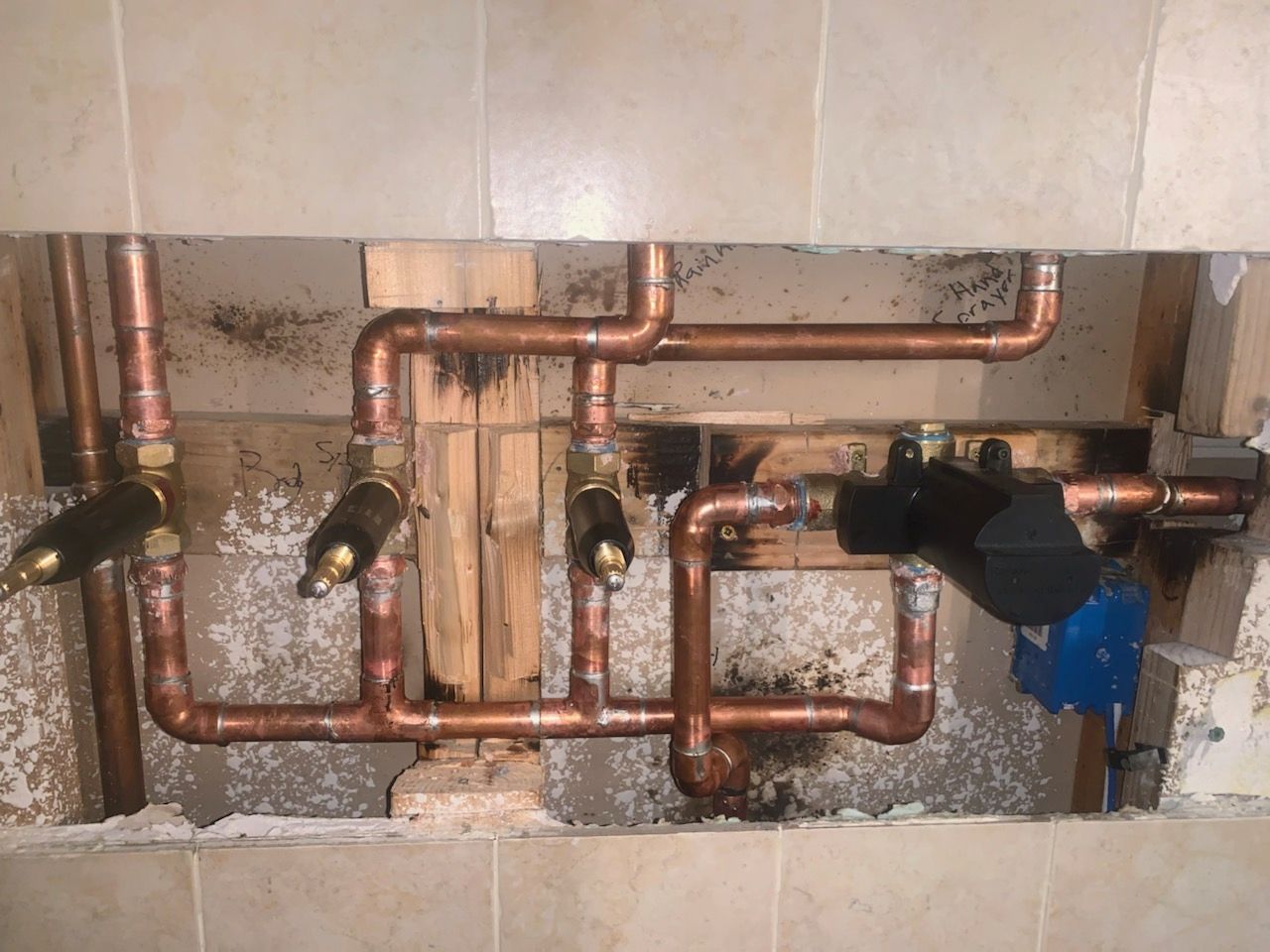 Copper plumbing pipes and shutoff valves installed behind a wall opening.
